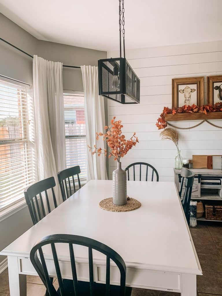 White farmhouse table decorated for fall with white shiplap walls and a new dining table light fixture. 