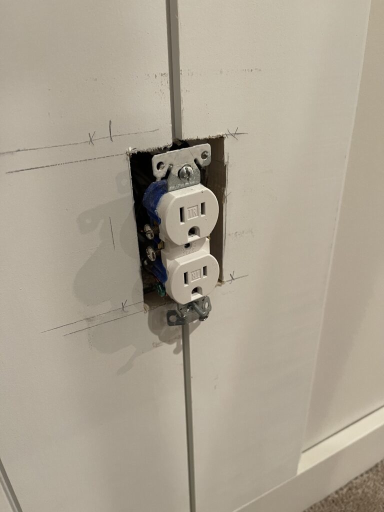 Outlet in the middle of 2 vertical shiplap boards.